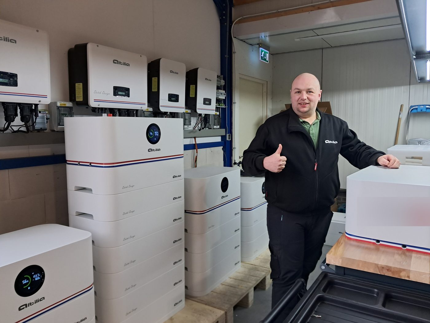 Collega in Altilia-jas steekt zijn duim op tussen de stapelbatterijen in de testruimte