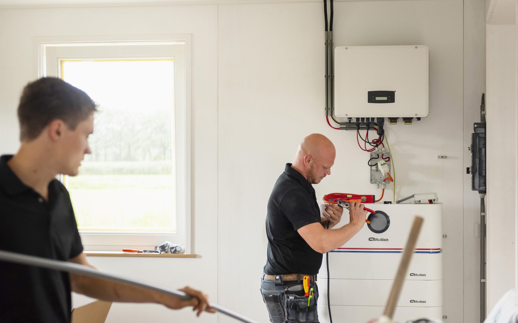 Twee installateurs monteren een Altilia omvormer en stapelbatterij