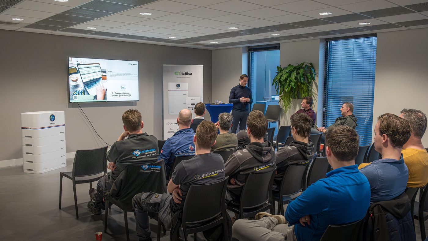 Installateurstraining: een volle zaal installateurs luistert naar een presentatie, met een Altilia stapelbatterij vooraan