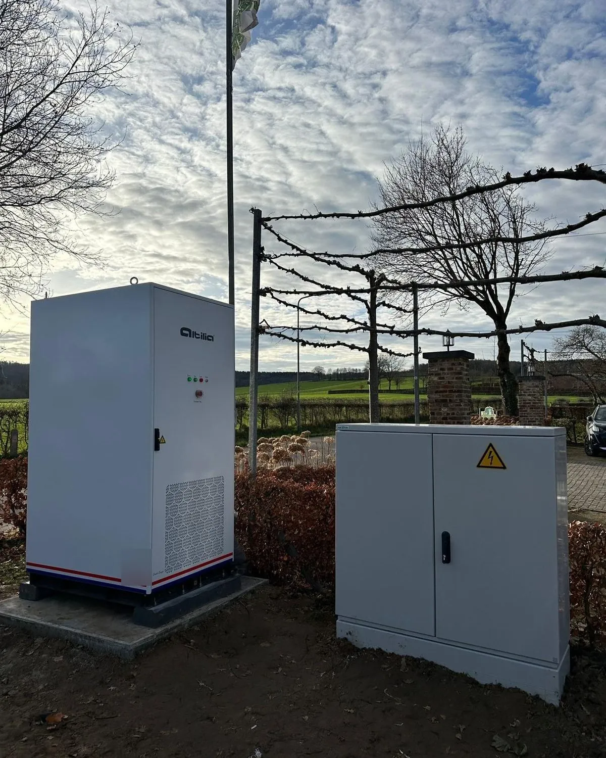 Energieopslagsysteem van Altilia buiten naast een verdeelkast, onder een wolkenlucht
