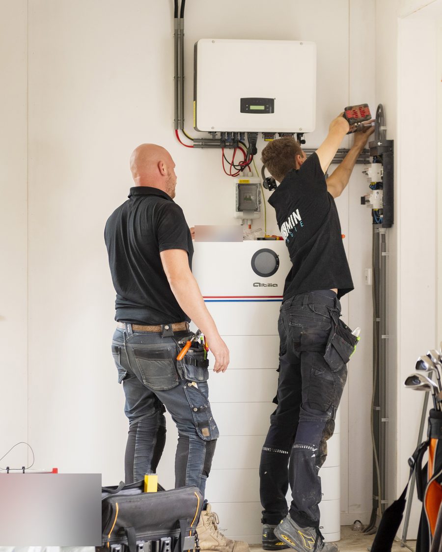 Twee installateurs monteren de bekabeling boven een Altilia stapelbatterij