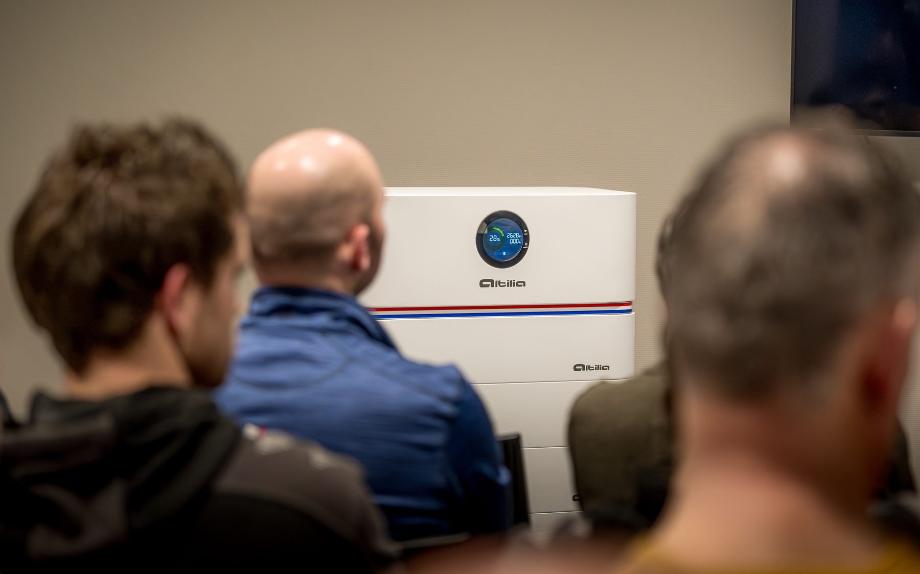 Publiek luistert naar een presentatie, met een Altilia stapelbatterij op de voorgrond
